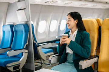 Young Asian executive excels in first class, multitasking with digital tablet, laptop and...