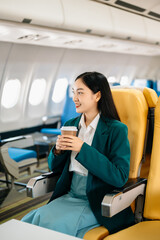 Fototapeta na wymiar Young Asian executive excels in first class, multitasking with digital tablet, laptop and smartphone. Travel in style, work with grace. in morning light.
