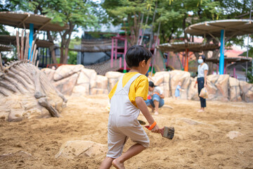 Asian kindergarten 5 year old playing in sandbox having fun on playground in sandpit.