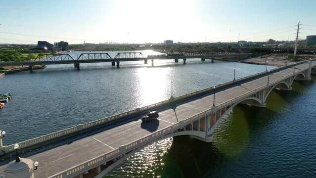 Tempe Bridge over Salt River and Tempe Town Lake in Tempe, Arizona. Aerial shot of bridge and traffic during bright sunset in AZ reflected by water.