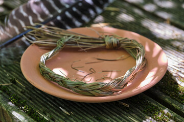 Sweetgrass braid (Hierochloe odorata), also called vanilla grass, and smudging feather outdoors in summer