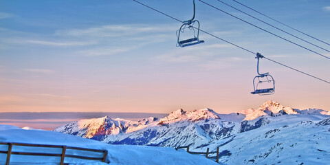 Ski lift and snowy mountains in the background at sunset - obrazy, fototapety, plakaty
