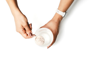 Woman's hands with measuring spoon puts portion of whey protein powder into a shaker, making...