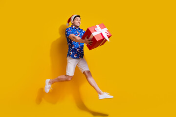 Fototapeta na wymiar Full body portrait of crazy cheerful person jump hands hold giftbox empty space isolated on yellow color background