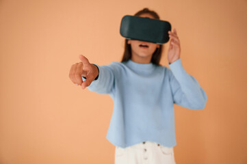 Trying VR glasses. Cute young girl is in the studio against background