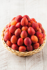 Ripe juicy apricots in a wicker basket on a white background. Harvesting.