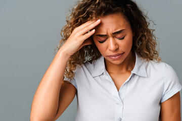 Fototapeta premium Portrait of a beautiful woman with pale wavy hair in a white short-sleeved shirt with a severe headache