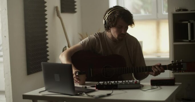 Guitarist with coffee at desk with netbook