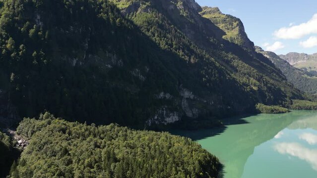 gigantic mountains prostrate across the location creating eye-catching landmark for experienced hikers to climb these rocky steep hills clear still water lake with reflections of clouds in it peaceful