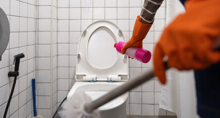 A woman asian clean a bathroom toilet with a scrub brush