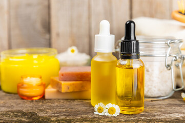 Chamomile spa. Composition with chamomile flowers, handmade soap, essential oil cosmetic bottle, body cream, scrub and sea salt on a white texture background. Relaxing beauty treatments.Copy space