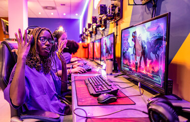 concentrated young african woman playing video games in a team battle Esport game, © PintoArt