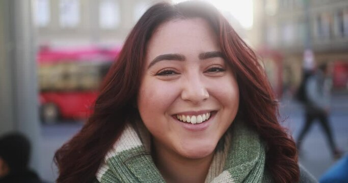 Young multiracial woman smiling in front of camera at bus station during winter time 