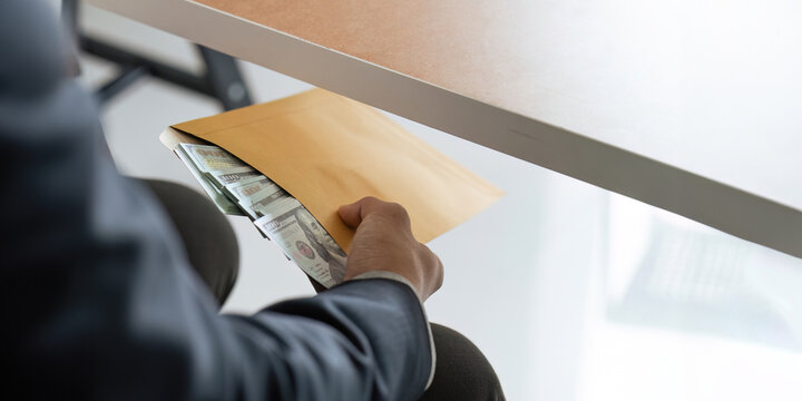 Businessman briefcase document envelope with dollar banknotes while money passes under a table. business accept illegal secret agreement money. concept corruption, bribery, crime and embezzle