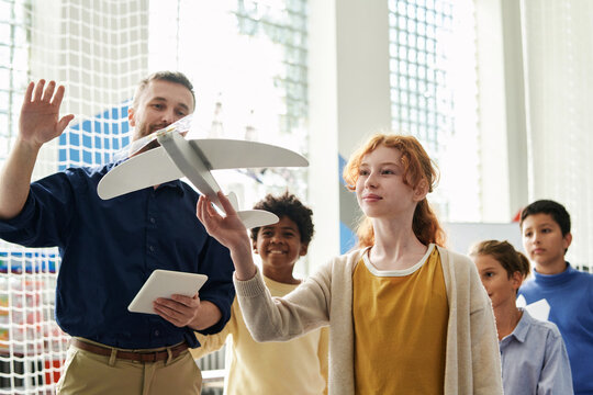 Friends looking at girl launching her radio controlled plane model - Powered by Adobe
