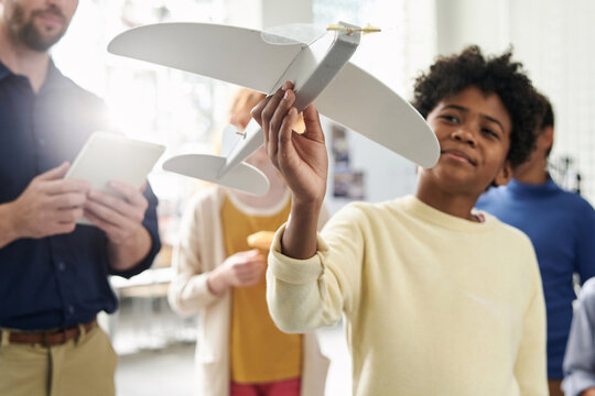 Proud boy holding radio controlled plane model he made in class