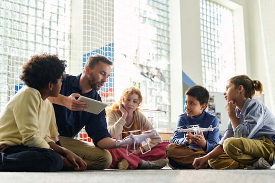 Teacher explaining group of children safety precautions before launching flying drones