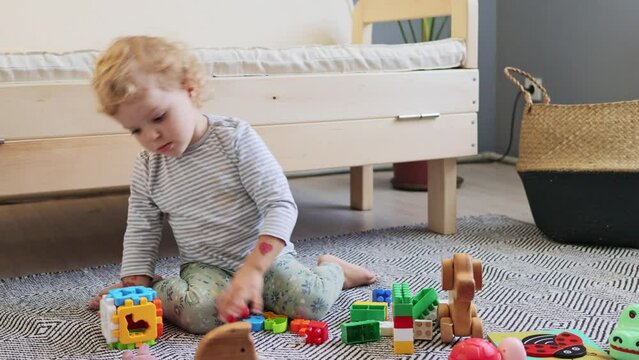 Logic games for kindergarten. Fun and development for toddlers. Educational games for kids. Cute baby's playtime. Blond little kid girl playing with toys alone in home interior.