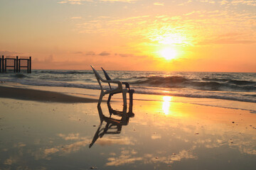 Plastic chairs reflecting with the waves