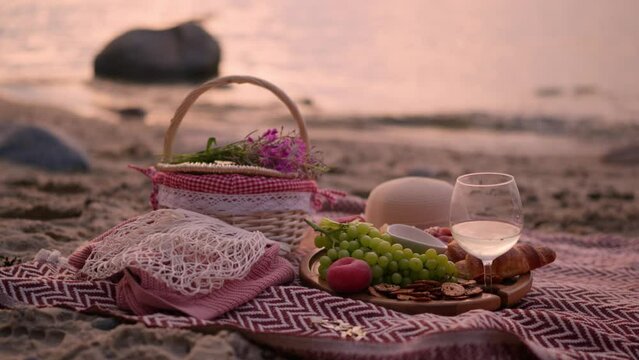 Beautiful summer picnic at sunset on beach with white wine, croissants, cheese and fresh fruits.