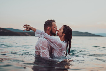 A romantic young couple sharing a passionate kiss amidst the serene beauty of the ocean at sunset.
