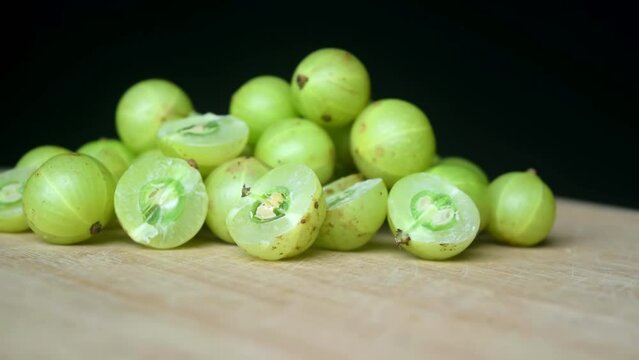 Green amla into the wooden table black background slow-motion