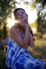 Jeune femme blonde dans la nature au coucher de soleil, mains sur le visage