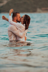 A romantic young couple sharing a passionate kiss amidst the serene beauty of the ocean at sunset.
