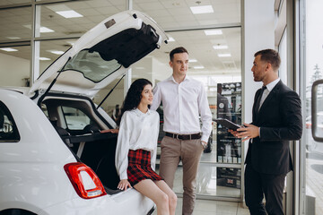 Young couple shaking hands with sales agent after a successful car buying.