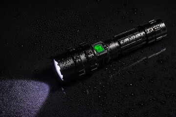 Tactical waterproof flashlight with waterdrops on black background - obrazy, fototapety, plakaty