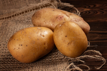 Raw potato food. Fresh potatoes in an old sack on wooden background