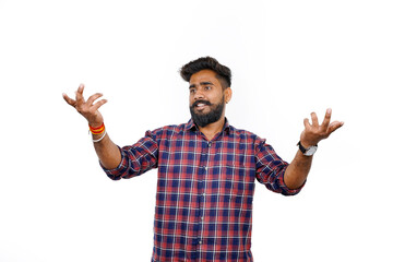 Young Indian man standing alone against a white background, looking at the camera with a stunned...