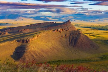 Awe landscape of sunny sunset on Sunduki mountain range at early autumn day in Khakassia. View on Chest rock. Location in valley of the Bely Iyus River in republic of Khakassia, Russia - obrazy, fototapety, plakaty