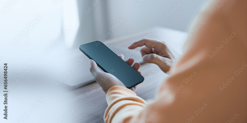Poster Young man holding and using a smartphone with blank desktop screen while working and drinking coffee in cafe. Mockup mobile phone.
