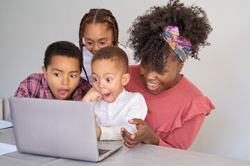 Happy african family look at laptop screen surprised at home.