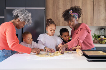 African family cutting cookie shapes in a cookie dough in the kitchen. Horizontal extended family.