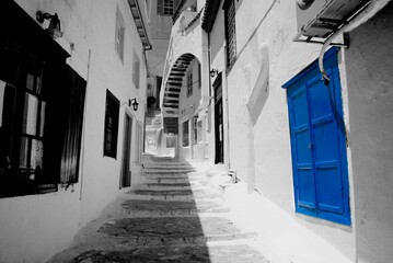 Viuzza in un paese greco con portone colore bleu e sfondo in bianco e nero