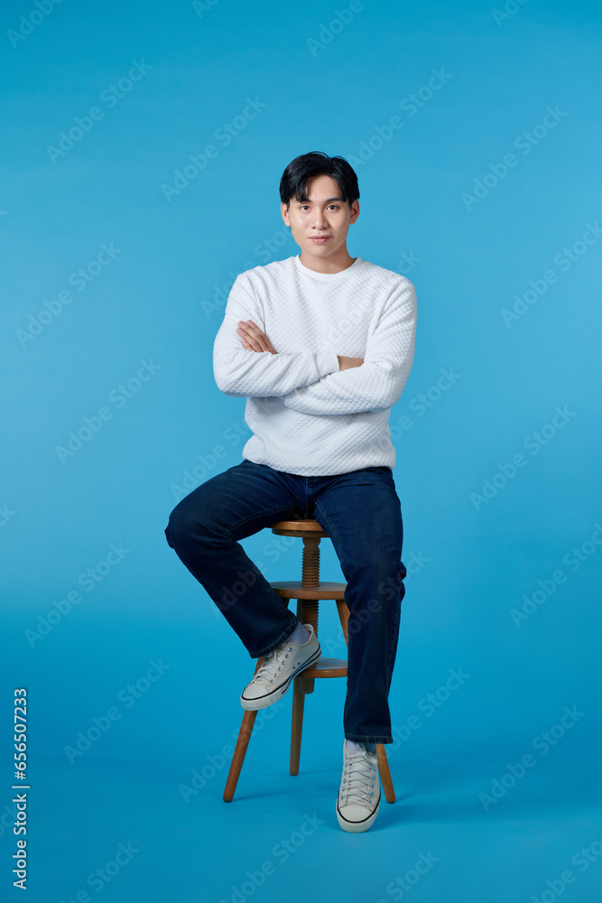 Wall mural Happy smart casual man smiling with his hands folded while sitting on a chair