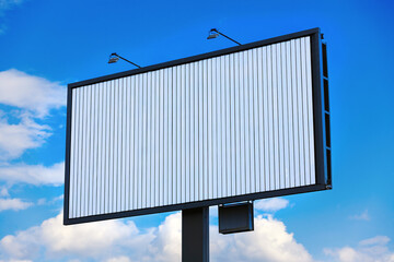 Blank white billboard mockup at grey frame. Trivision against blue sky background. A Trivision,...