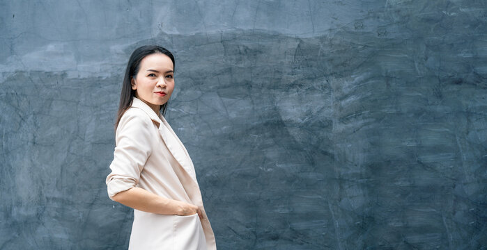 Portrait of successful business asian woman in grey suit with smile isolated over blue background. Business stock photo.