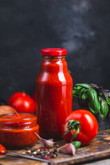 Ketchup in a jar. Tomato sauce on a dark background
