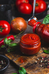 Ketchup in a jar. Tomato sauce on a dark background