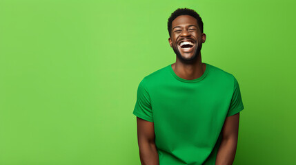 Fototapeta premium Ultra handsome black african, smiling and laughing, wearing green clothes. Bright solid green background.