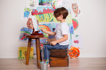 Child painting displaying his artwork on the wall.  watercolor painting a masterpiece 