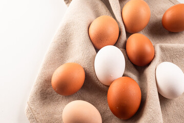 Chicken eggs on linen napkin on white background.