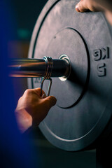 male athlete trainer adds weight to the barbell in the gym increases the load on the body of the...
