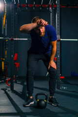 Fototapeta na wymiar portrait of a tired athlete in the gym after training a man wipes sweat from his forehead with his hand