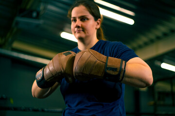 portrait of a woman in boxing gloves posing in a cheeky and competitive fight in a boxing ring before a fight with an opponent