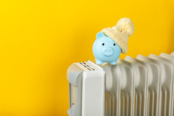 Savings concept.Money in piggy bank on radiator on yellow wall background. Concept of heating...