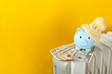 Savings concept.Money in piggy bank on radiator on yellow wall background. Concept of heating...